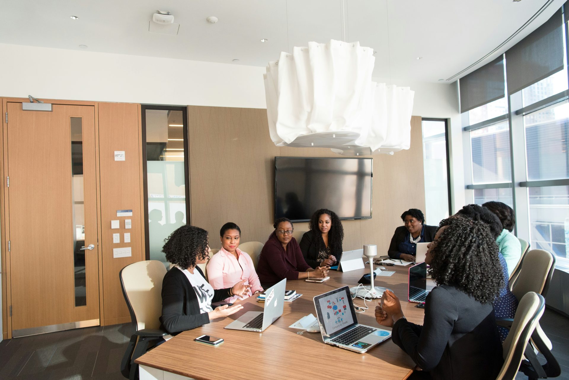 Group of professional black women meeting around the table while working on their laptops