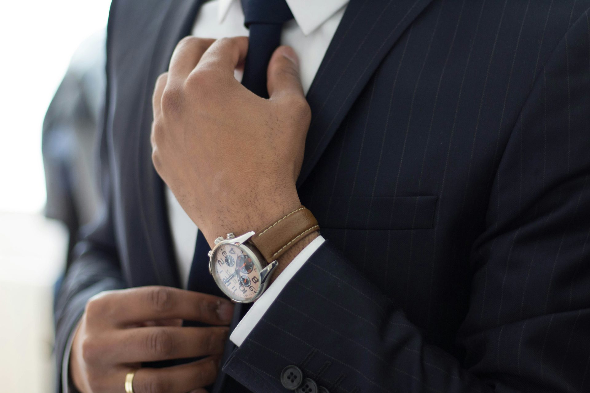 Professional in suit putting his hands on his tie